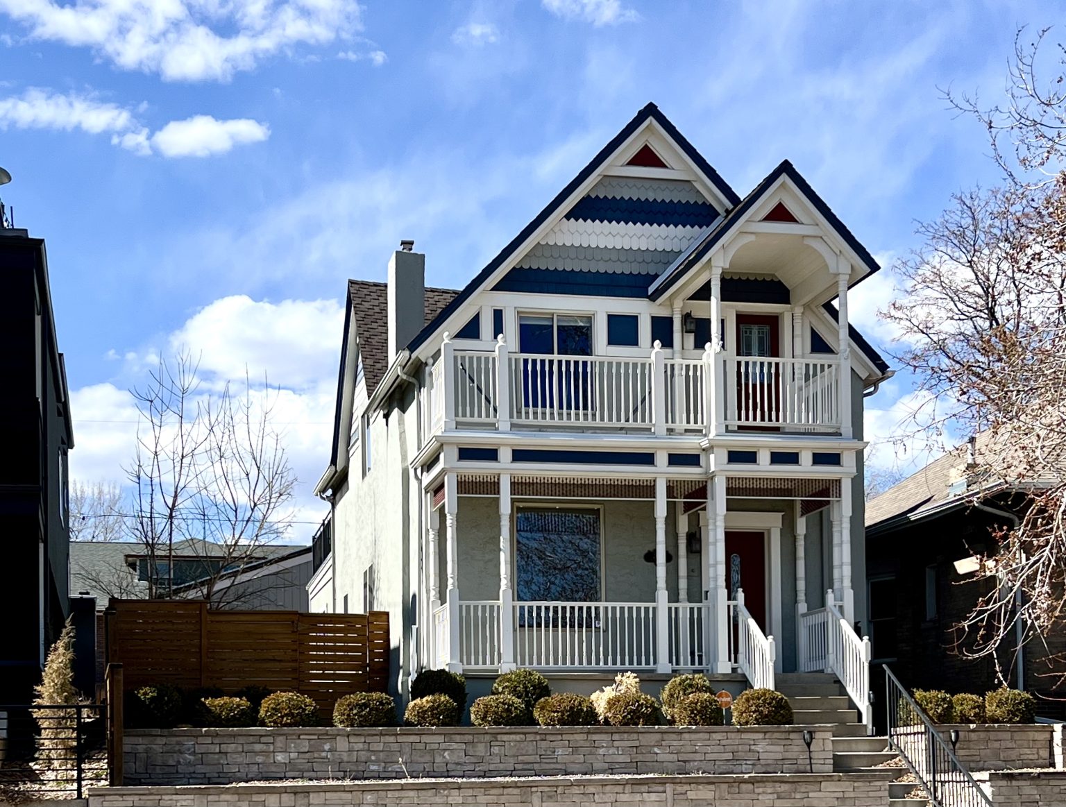 A beautifully restored Victorian-style home in Denver's Jefferson Park neighborhood, featuring a charming front porch, intricate trim details, and a second-story balcony against a blue sky. This home embodies the architectural charm and urban convenience of one of Denver’s most sought-after neighborhoods.