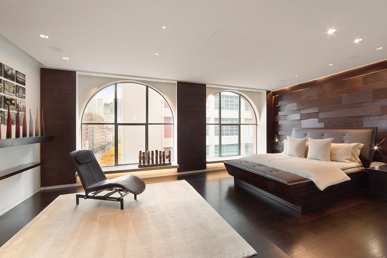 Modern primary bedroom with arched windows and skyline views in luxury Denver condo