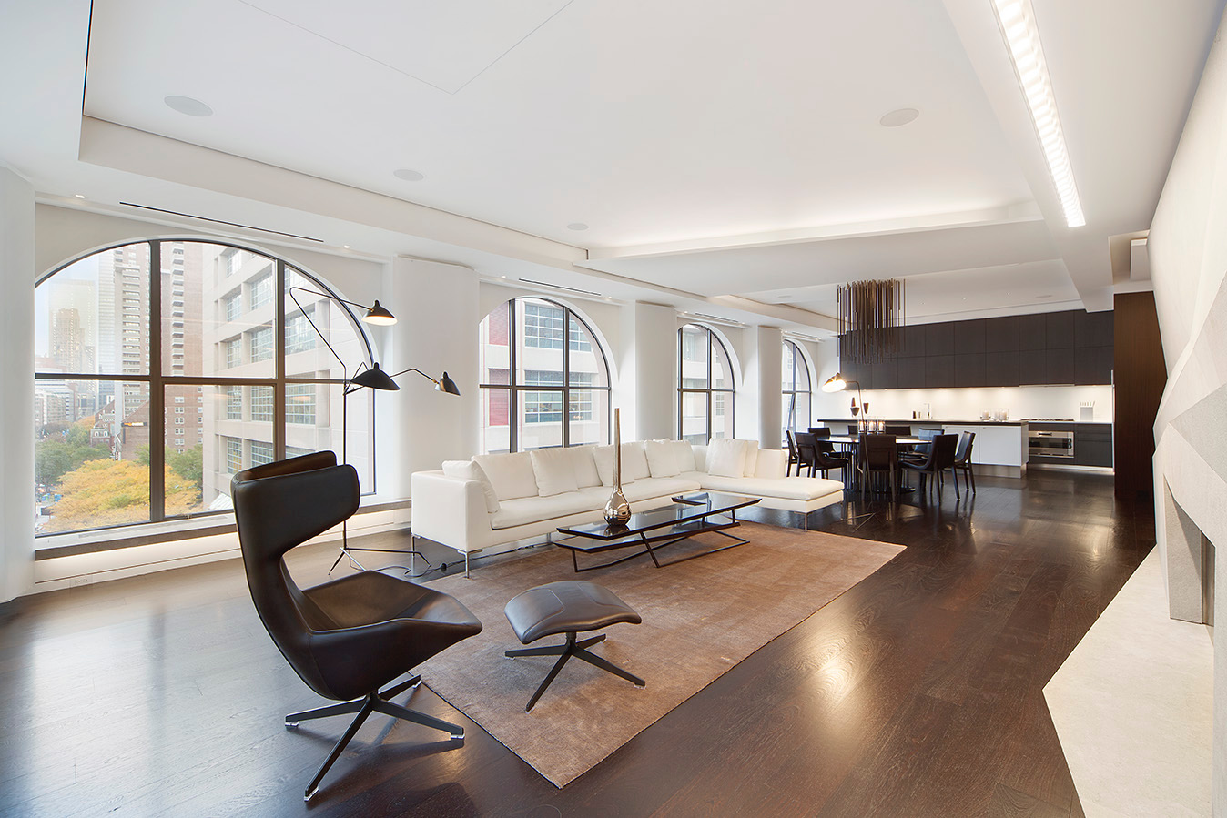 Open-concept living and dining area with designer lighting and dark hardwood floors