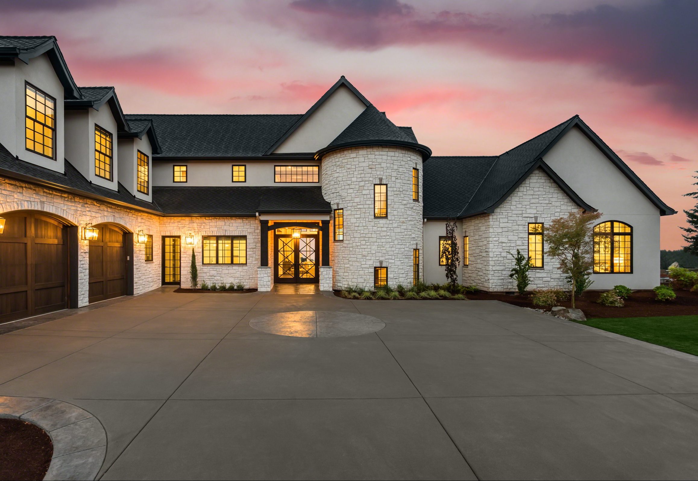 Elegant French country estate with white stone exterior, turret entry, and warm ambient lighting at sunset.